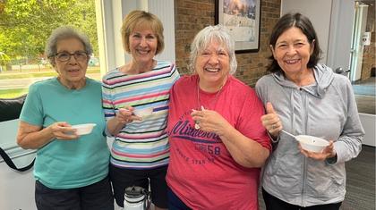 Four older women smiling and holding bowls